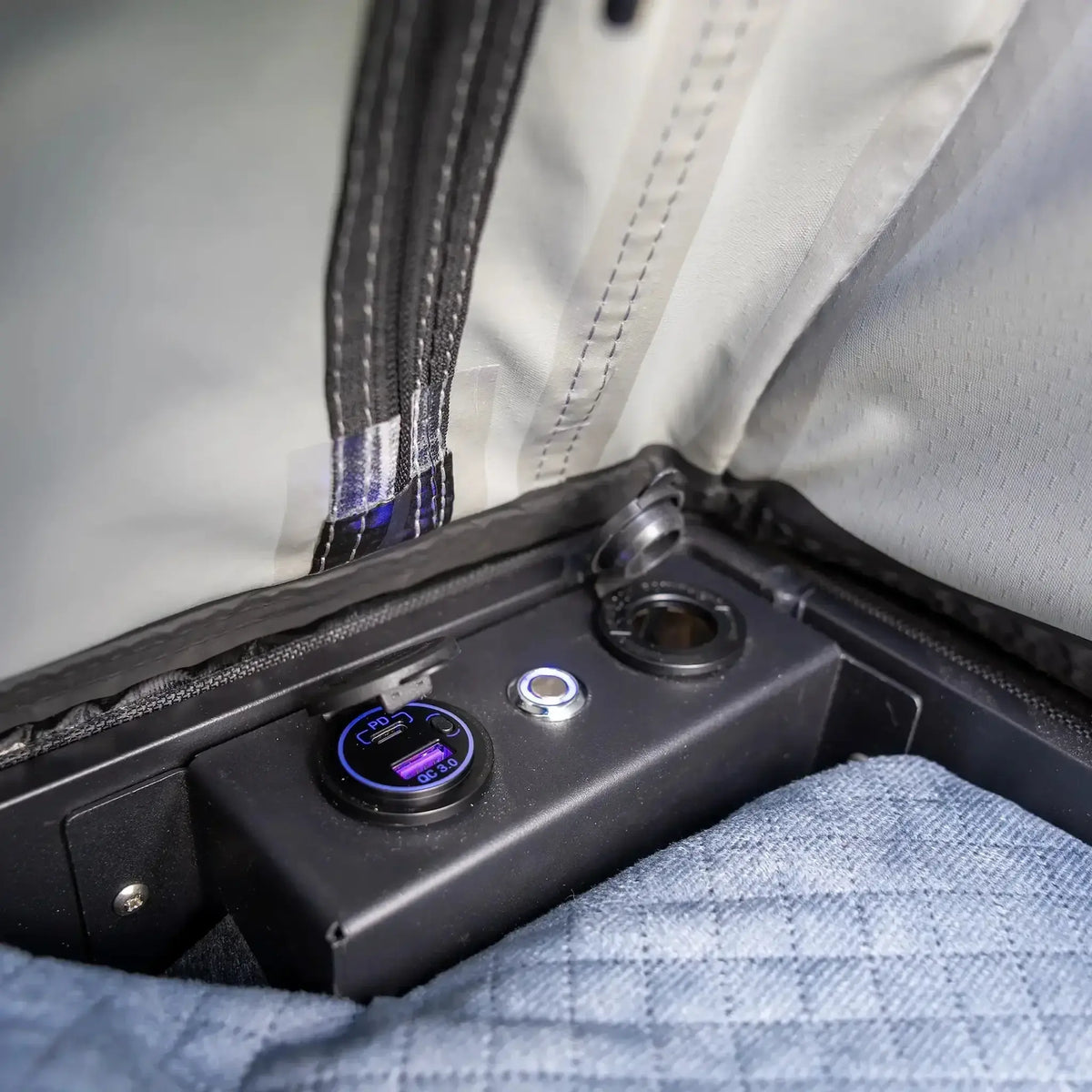Bushwakka Stellar rooftop tent power panel close up with USB ports, a socket and an illuminated switch.