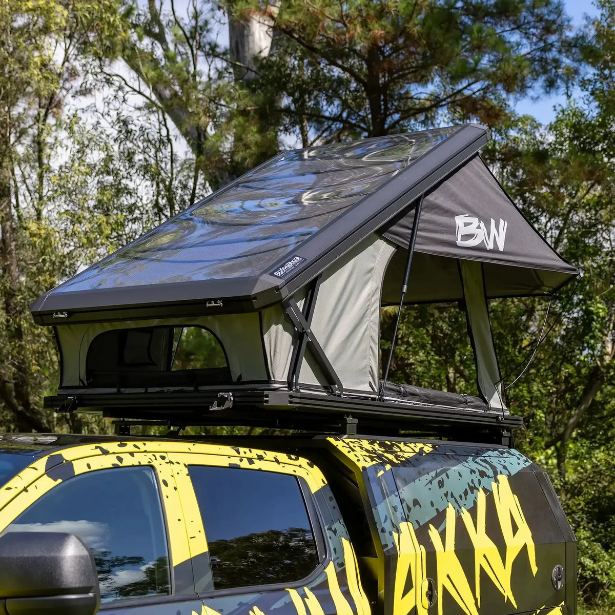 Bushwakka Stellar rooftop tent mounted on a vehicle with the clear roof raised and rain fly at the rear.