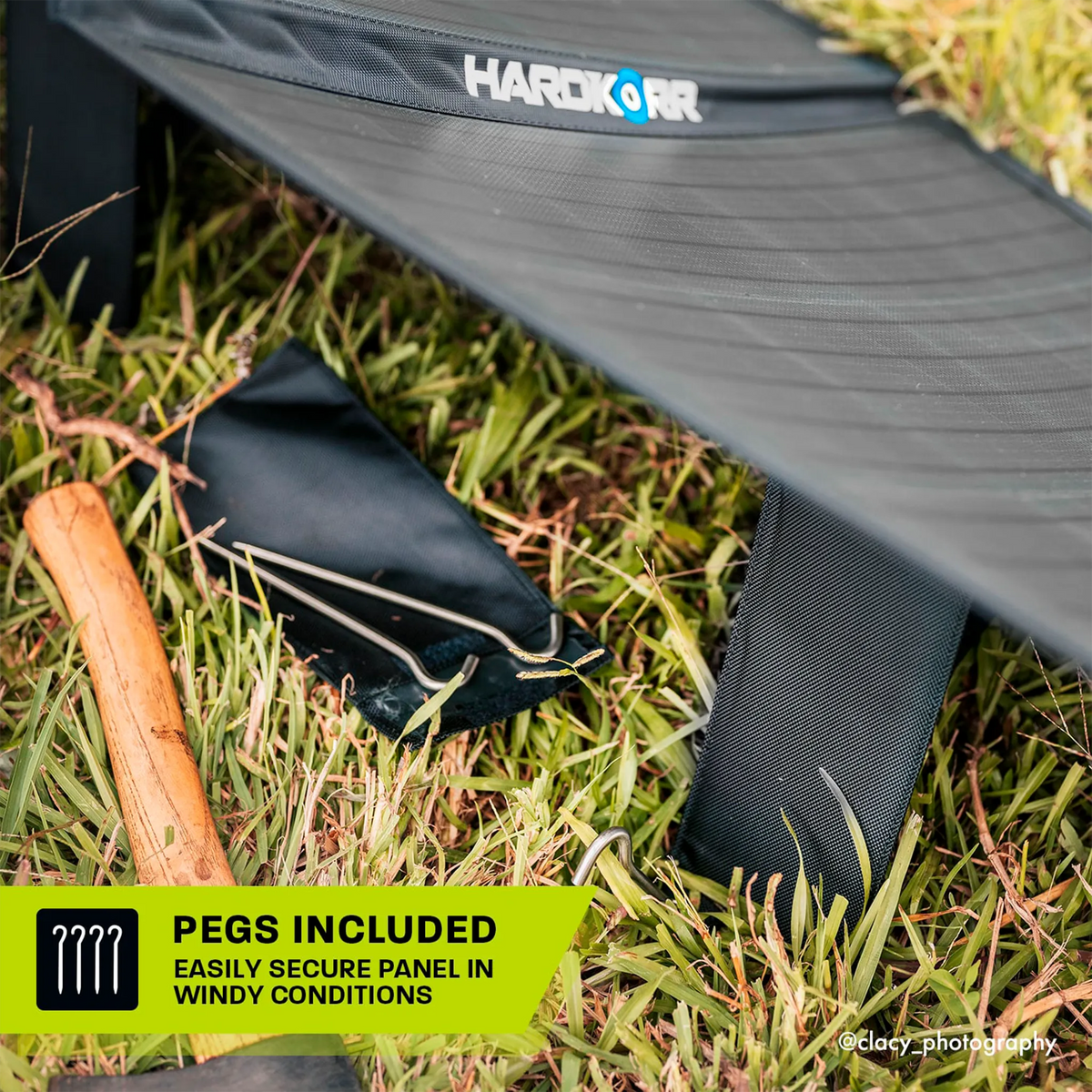 Hardkorr 150W 12V portable solar mat rear leg close up with a ground peg and hammer in grass.
