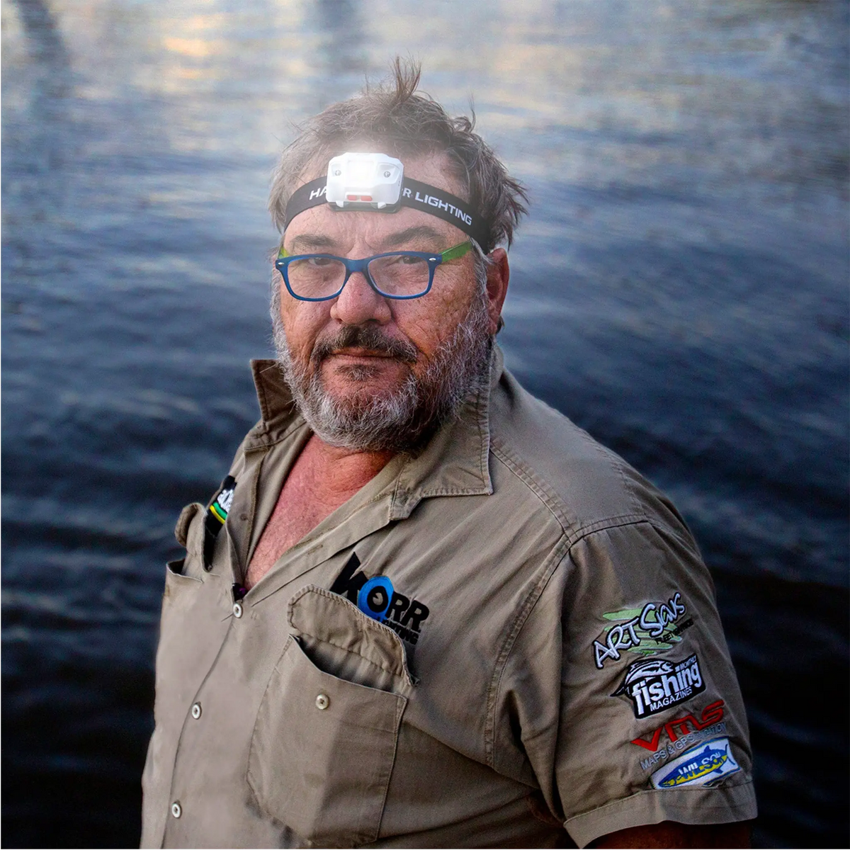 Hardkorr 335 lumen headtorch worn by a man beside the water with the white light on.