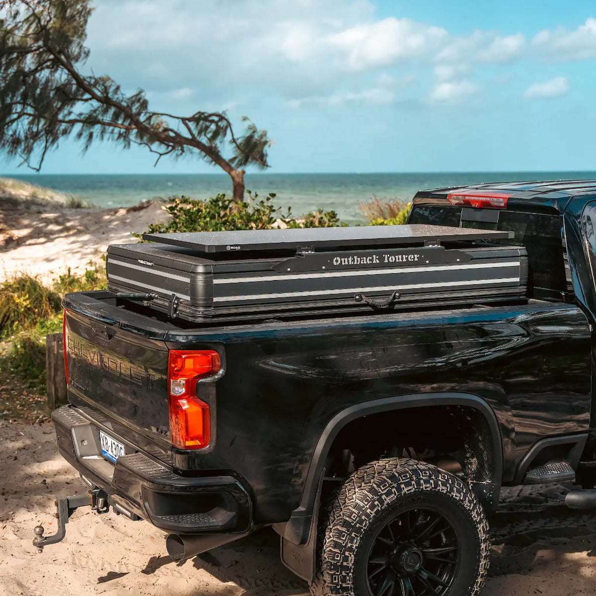 Outback Tourer 1.9 Pro Rooftop Tent closed on a tub rack at a beach campsite.