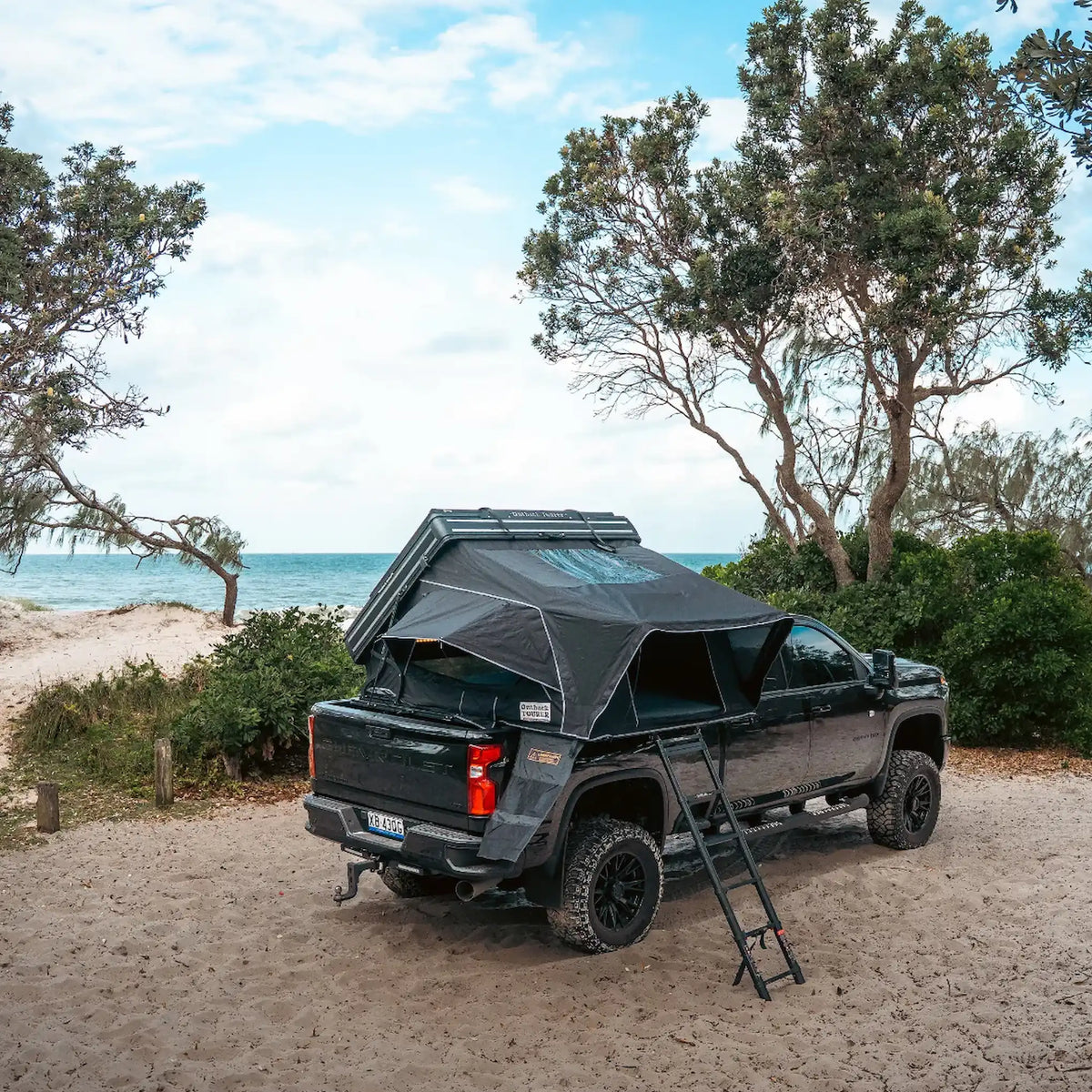 Outback Tourer 1.9 Pro Rooftop Tent open rear view on a ute near the beach.