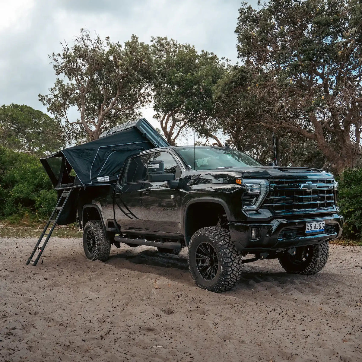 Outback Tourer 1.9 Pro Rooftop Tent front right open view on a black ute in sand.