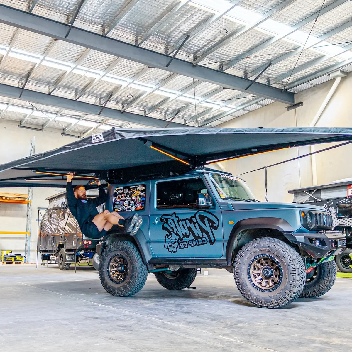 Outback Tourer Drivers Side 270 Plus X-Tend Awning front right view open on a blue vehicle.