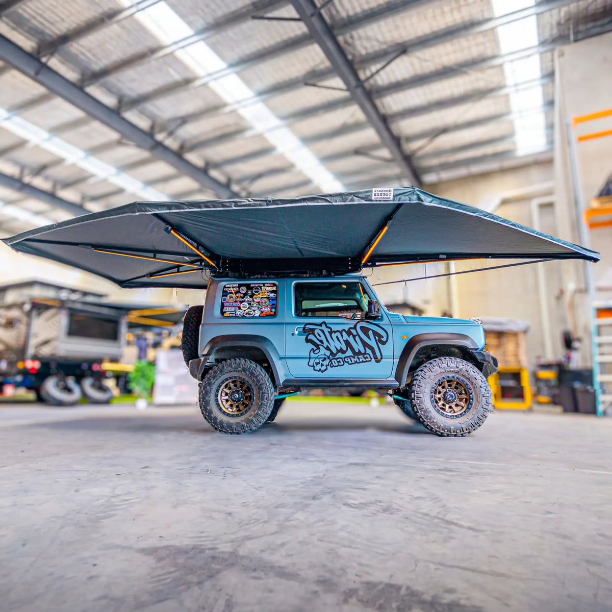 Outback Tourer Drivers Side 270 Plus X-Tend Awning side underside view on a blue Jimny in a workshop.