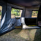 Bushwakka Extreme Darkness awning wall kit interior view with mesh windows, a chair and the vehicle beside it.