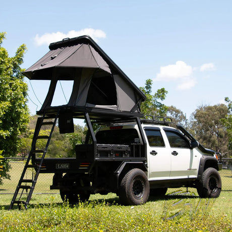 Bushwakka Doghouse rooftop tent rear installed view on a ute with ladder and rain fly extended.