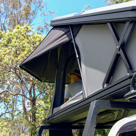 Bushwakka Doghouse rooftop tent installed side close up with rain fly on steel poles and window open.