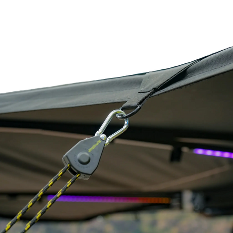 Bushwakka Driver Side Darkness 270 Pro Awning tie-down strap and hook attached to the awning edge.