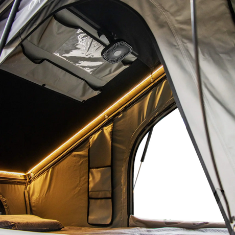 Bushwakka Shack rooftop tent interior view with amber strip lighting, an open doorway and a ceiling fan.