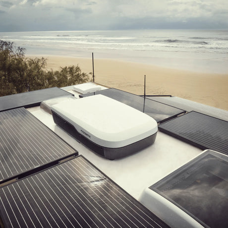 Dometic FreshJet 7 Series Pro white rooftop air conditioner installed on an caravan roof with solar panels.