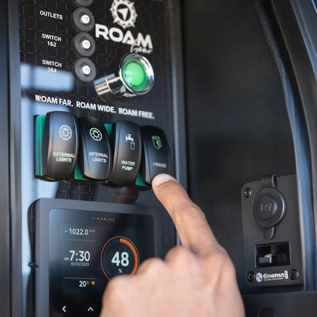 A hand presses the fridge switch on an installed Enerdrive Explorer power system with a Simarine monitor.