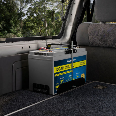 Hardkorr 100Ah lithium battery tray installed in a vehicle rear cargo area with the battery secured inside.