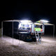 Hardkorr 100cm LED light bar kit casting white light over a camper trailer kitchen and the ground at night.