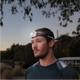 Hardkorr 145 lumen headtorch worn by a man outdoors at dusk with the light on.