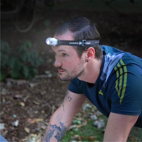 Hardkorr 155 lumen slimline headtorch worn by a man leaning forward outdoors with the light on.
