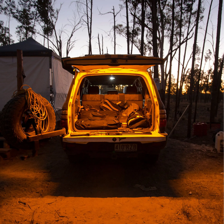 Hardkorr 1m LED tape light casting orange light over a vehicle's open rear cargo area and the ground.