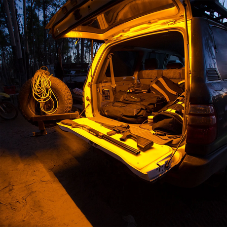 Hardkorr 1m LED tape light close up around a rear hatch, lighting the cargo area and tailgate in orange.