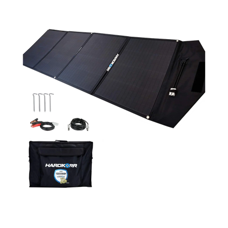 Hardkorr 200W 12V portable solar mat unfolded beside its carry bag, pegs and positive and negative battery clamp lead.