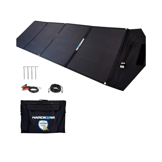 Hardkorr 200W 12V portable solar mat unfolded beside its carry bag, pegs and positive and negative battery clamp lead.