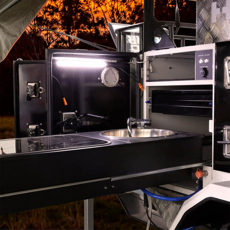 Hardkorr 25cm LED light bar casting white light over a camper kitchen sink and cooktop.