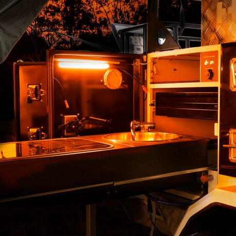 Hardkorr 25cm LED light bar casting orange light over a camper kitchen sink and cooktop.