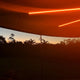 Hardkorr 3 strip LED awning light kit glowing orange along the awning arms at dusk.