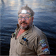 Hardkorr 335 lumen headtorch worn by a man beside the water with the white light on.