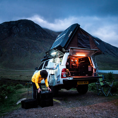 Hardkorr 50cm LED light bar kit casting white and orange light around a vehicle while a person packs gear.