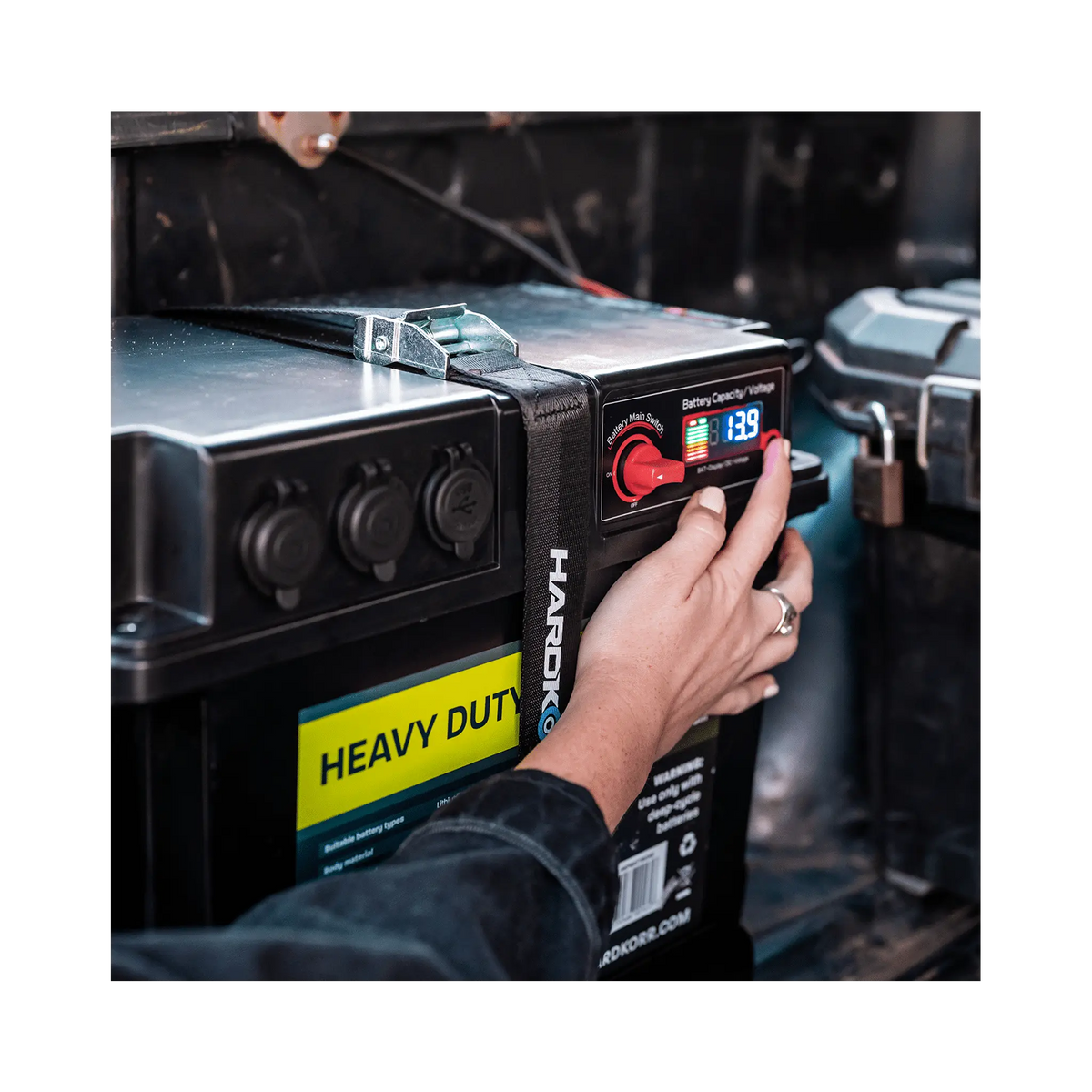 Black Hardkorr battery box control panel close up with a finger on the button beside the lit display.