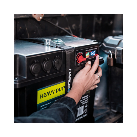 Black Hardkorr battery box control panel close up with a finger on the button beside the lit display.