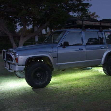 Hardkorr High Powered Rock Lights illuminating the ground beneath a parked Nissan Patrol.