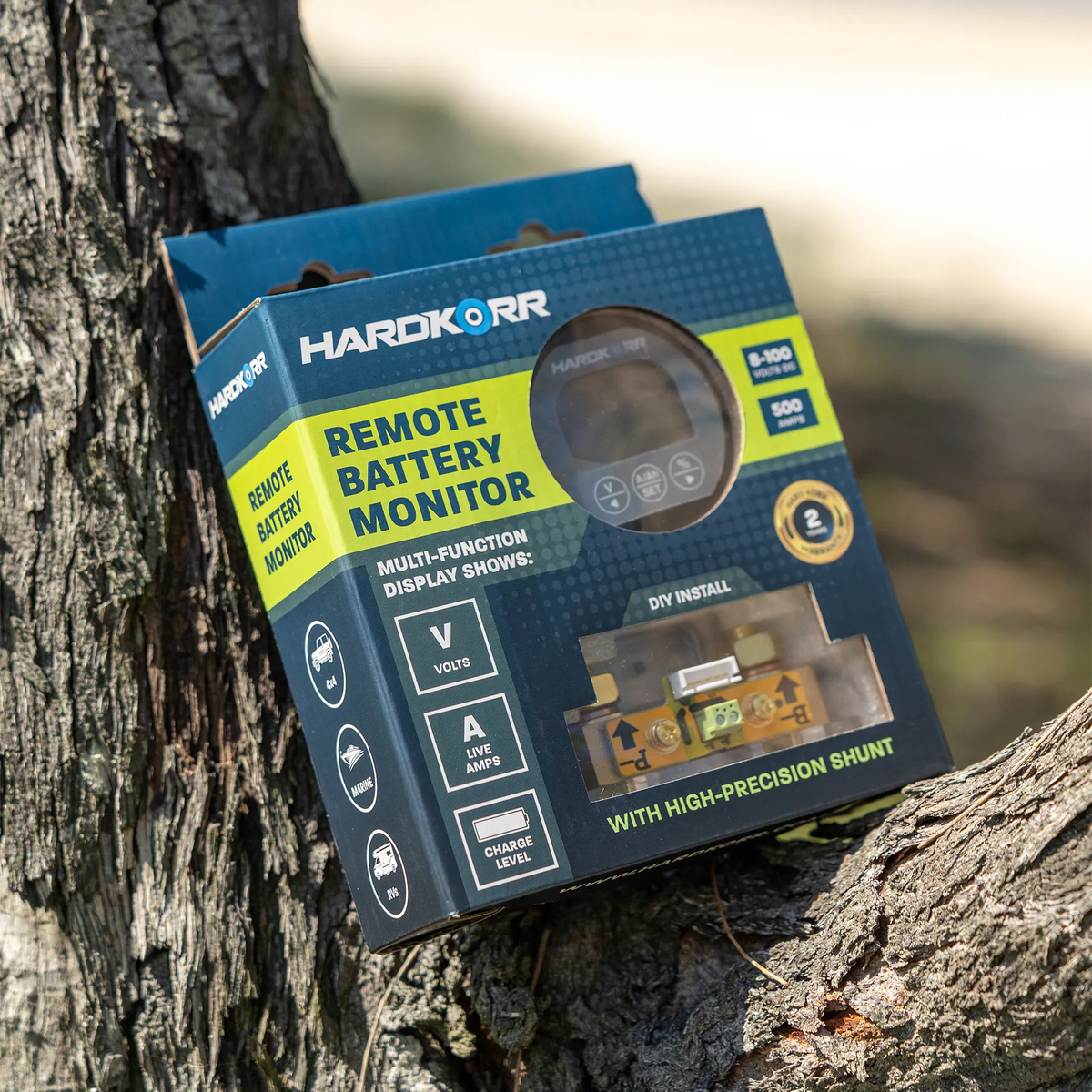Hardkorr remote battery monitor retail packaging resting in a tree fork with its labelled front visible.