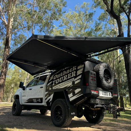 Outback Tourer 180 Awning rear installed view opened above the back of a vehicle at a campsite.