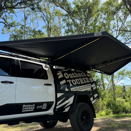 Outback Tourer 180 Awning side installed view opened above a white vehicle at a campsite.