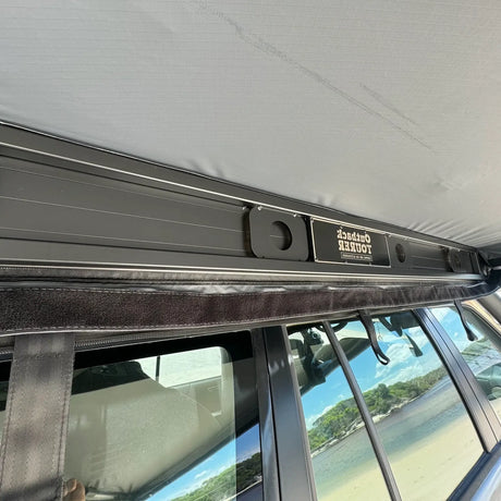 Outback Tourer Drivers Side 270 Awning powdercoated frame with logo plaque with the vehicle on the beach.