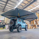 Outback Tourer Drivers Side 270 Plus X-Tend Awning rear underside view on a blue Jimny in a workshop.