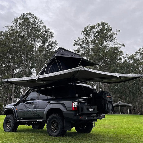 Outback Tourer Passenger Side 270 Awning back left view with a rooftop tent on a grass campsite.