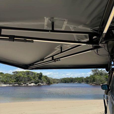 Outback Tourer Passenger Side 270 Awning underside view with support arms above a beach river.