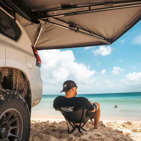 Outback Tourer Passenger Side 270 Plus Awning side underside view above a person on a beach chair looking at the ocean.