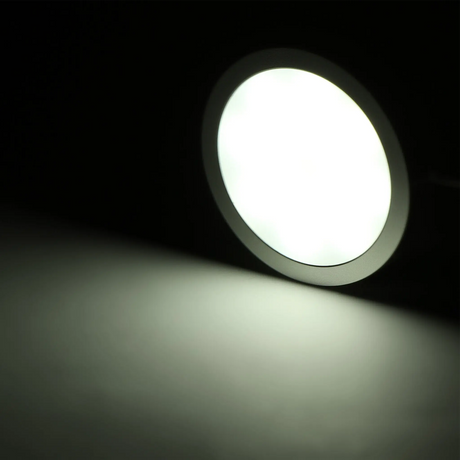 Rekcharge 12V black cool white LED downlight illuminated against a dark background.