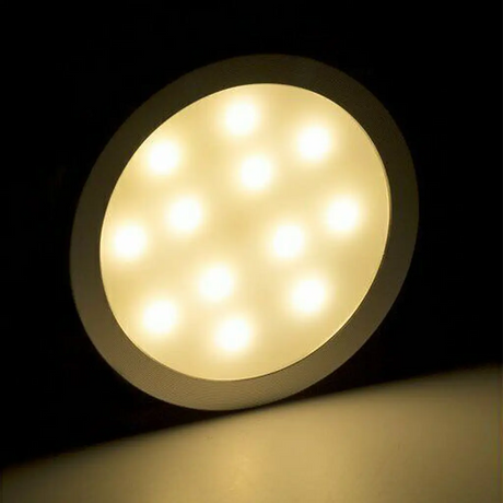 Rekcharge 12V silver warm white LED downlight casting warm light onto the surface below.