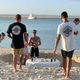Two men wearing the Roam Gear "Live the Roam Life" T-shirt from the rear at a beach gathering.